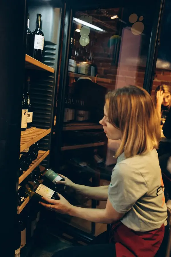 Dominika Szpakowska selecting a bottle from the wine cooler at Pijalni