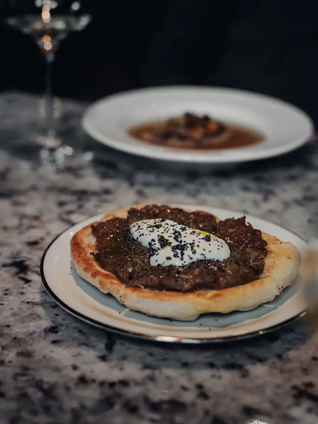 Płaski chlebek z grilla obok kieliszka wina naturalnego w Pijalnych