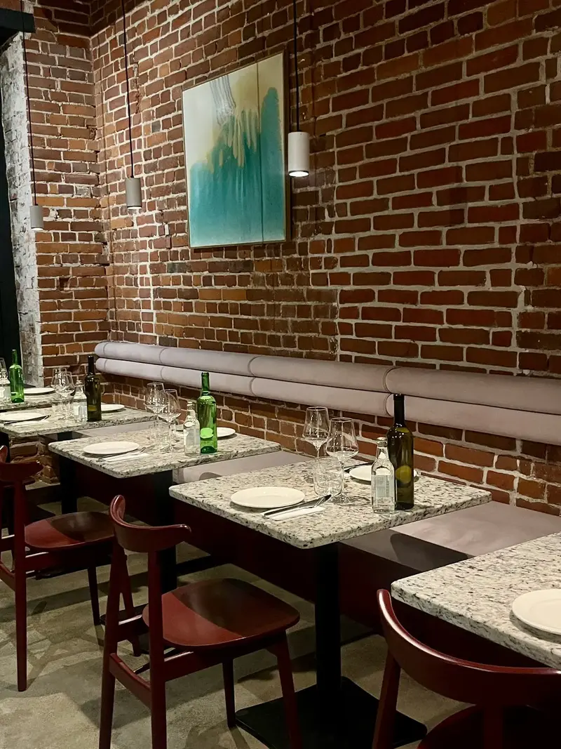 Gastraum des Pijalni mit gedeckten Tischen und Backsteinwand